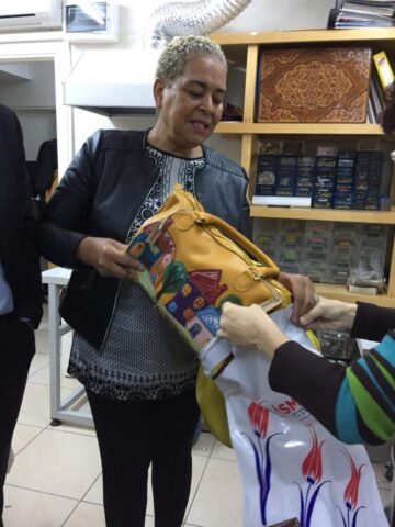 Ziyaretçimizin ellerinde tuttuğu el yapımı çanta, ustalığın ve tasarımın birleşiminden doğmuş özel bir ürünü temsil ediyor. Canlı renklerle işlenmiş detaylar, geleneksel motiflerin modern bir yorumu olarak dikkat çekiyor. Çantanın taşıdığı kültürel dokunuşlar ve özgün tasarımı, hem estetik hem de işlevsellik açısından fark yaratıyor. Ürünümüzü inceleyen her bakış, el emeğinin değerini ve zanaatın zarafetini bir kez daha ortaya koyuyor.