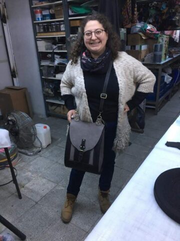 Katılımcımızın kendi elleriyle hazırladığı çantayı gururla taşıdığı bu karede, emeğin ve tasarımın mutluluğa dönüşmüş hâlini görmek mümkün. Deri detayları ve metal tokalarıyla dikkat çeken çanta, hem sağlamlık hem de estetik açıdan öne çıkıyor. Atölye eğitimlerimizde katılımcılar yalnızca teknik bilgi edinmekle kalmıyor, aynı zamanda kişisel zevklerini yansıtan özgün ürünler ortaya koyma fırsatı da buluyorlar. Bu tarz projeler, hem üretim sürecine dair becerileri geliştirmek hem de yaratıcılığı desteklemek açısından büyük önem taşıyor.