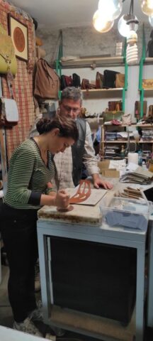 Bu fotoğrafta, çanta yapımı atölyemizde gerçekleşen bir eğitim anı görülüyor. Katılımcı, eğitmen rehberliğinde deri üzerine uygulamalı çalışma yapıyor. Geleneksel el işçiliği tekniklerinin aktarıldığı bu ortamda, katılımcılar birebir destek alarak üretim sürecinin her aşamasını deneyimleme fırsatı buluyor. El becerilerini geliştirmek, malzeme kullanımını öğrenmek ve özgün tasarımlar ortaya koymak isteyenler için atölyemiz sıcak, öğretici ve ilham verici bir buluşma noktası sunuyor.