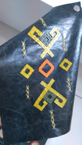 Bu motif, eski Türk kültürlerinde sıkça rastlanan göç ve yol temalı sembollerden esinlenerek tasarlanmıştır. Ortadaki turuncu ve yeşil geometrik şekiller, göçebe hayatın yön bulma ve denge arayışını temsil eder. Sarı tonlarındaki motifler ise yolculuğu, açıklığı ve yeni başlangıçları simgeler. Dik açılı köşeler ve spiral benzeri formlar, Orta Asya’dan Anadolu’ya uzanan kültürel aktarımın sembollerindendir. El işçiliğiyle doğal deri üzerine uygulanmış bu tasarım; çanta, duvar panosu veya özel koleksiyon parçaları için eşsiz bir kültürel motif sunar.