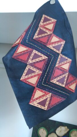 Bu tasarım, Anadolu kilimlerinde sıkça karşılaştığımız üçgen motiflerin modern bir yorumu olarak hayat buldu. Zikzak formundaki yerleşimi, doğanın ritmini ve yaşamın inişli çıkışlı yollarını temsil ederken; sıcak tonlardaki üçgenler birlik ve aile kavramlarına gönderme yapar. Her bir üçgen elde kesilip özenle dikilerek geleneksel deri işçiliği teknikleriyle bir araya getirilmiştir. Çanta, cüzdan, duvar dekoru gibi birçok üründe estetik bir vurgu olarak kullanılabilir. Hem nostaljik hem çağdaş bir dokunuş arayanlar için özgün bir seçenektir.