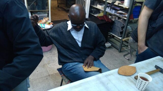 Evrensel Bir Sanat, Ortak Bir Dil: Deri Atölyemizden Bir An. Eğitim programlarımız, farklı kültürlerden katılımcılarla zenginleşiyor. El sanatlarının evrensel diliyle bir araya gelen katılımcılarımız, deri işçiliğinin inceliklerini birebir uygulamalarla öğreniyor. Fotoğrafta görülen kursiyerimiz, tamamen el dikişiyle bir deri ürünü oluştururken hem geleneksel Türk el sanatlarıyla tanışıyor hem de ustalığını geliştiriyor. Atölyelerimiz sadece üretim alanı değil, aynı zamanda paylaşım, öğrenme ve kültürel etkileşim alanlarıdır.