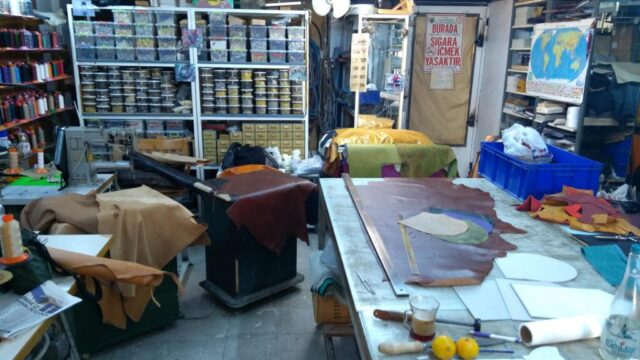 Her tasarımın hikâyesi burada başlıyor... Zanaatkârlarımızın elinde şekillenen deriler, geleneksel tekniklerle çağdaş estetiği buluşturan ürünlere dönüşüyor. Donanımlı atölyemiz, kaliteli malzeme seçimi ve ustalıkla yürütülen üretim süreçleriyle her bir ürüne ruh katıyor. Titizlikle organize edilmiş bu ortam, deri sanatının incelikle işlendiği bir üretim üssüdür.